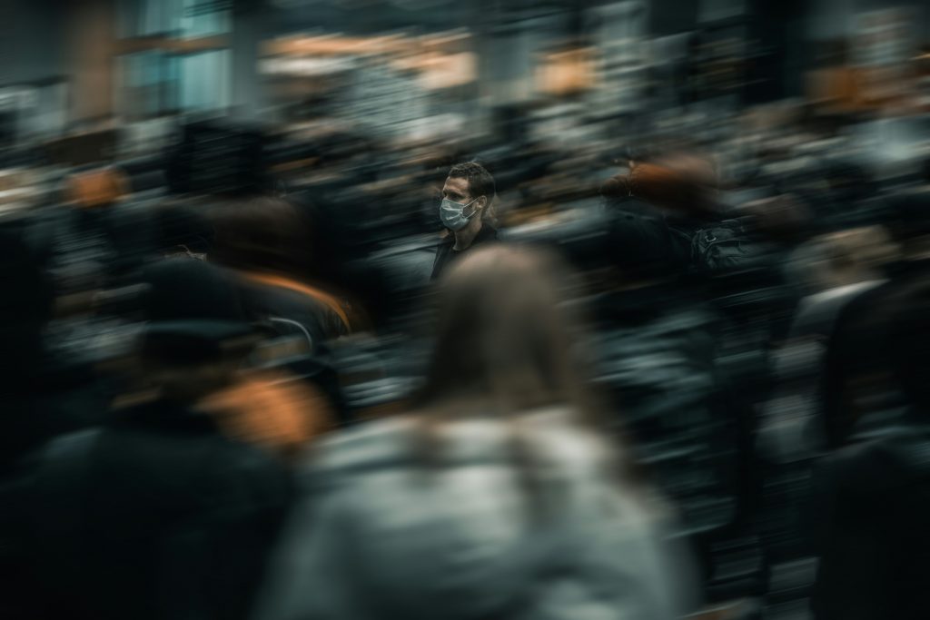 Man standing still in blurry crowd symbolizing stagnation.