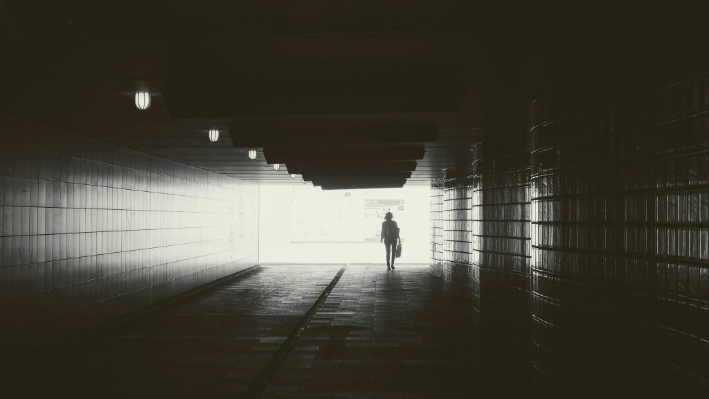 Man walking into light at end of tunnel symbolizing transformation.