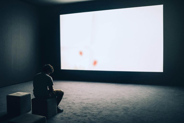 Man trapped by digital distraction, staring into a glowing screen in a dark room.