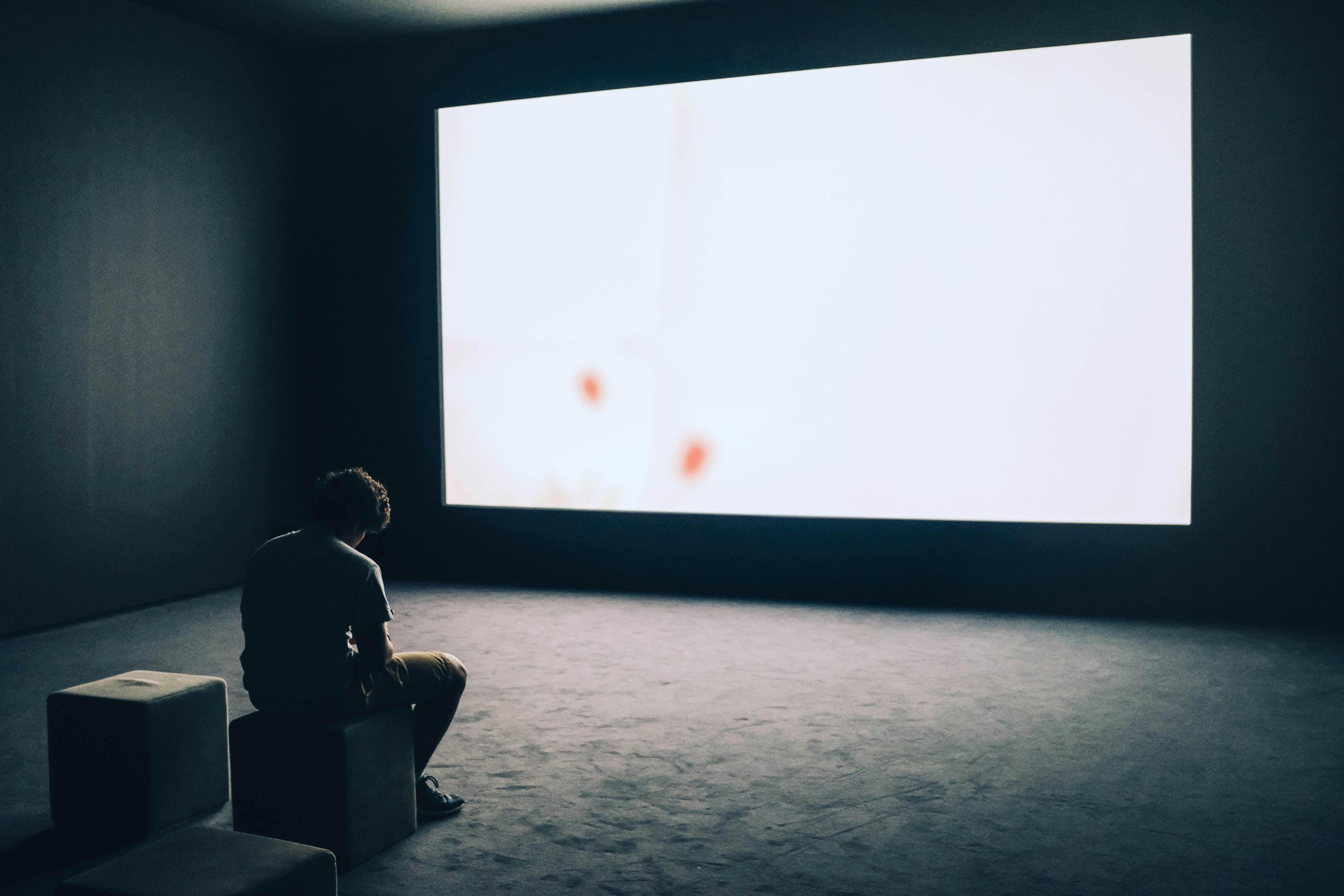 Man trapped by digital distraction, staring into a glowing screen in a dark room.
