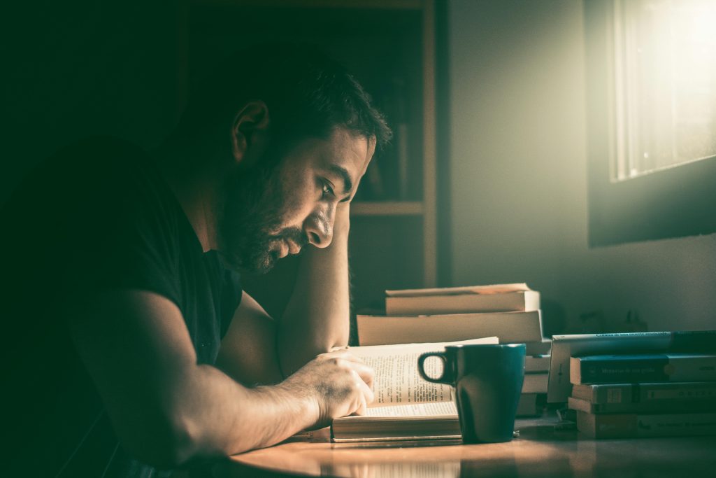 Man focused on reading at a clean desk with no digital distractions.