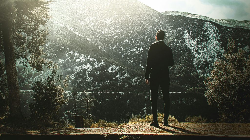Man sitting alone in nature, journaling or meditating quietly.