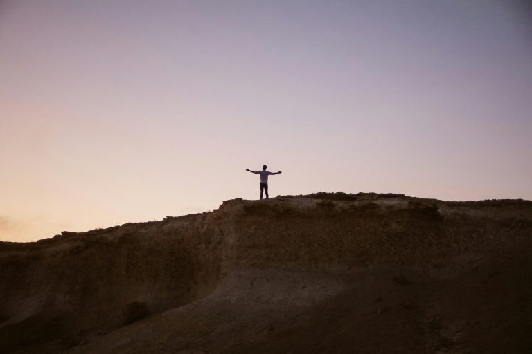Man searching for purpose on mountain summit.