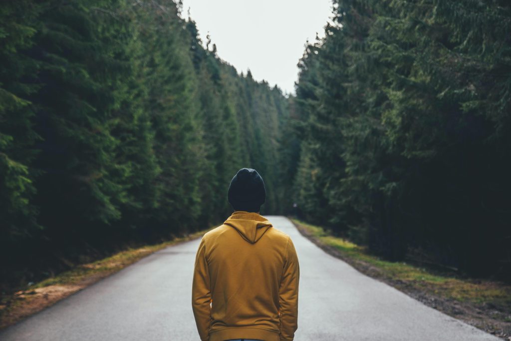 Man walking alone in the woods without a phone, deep in thought.