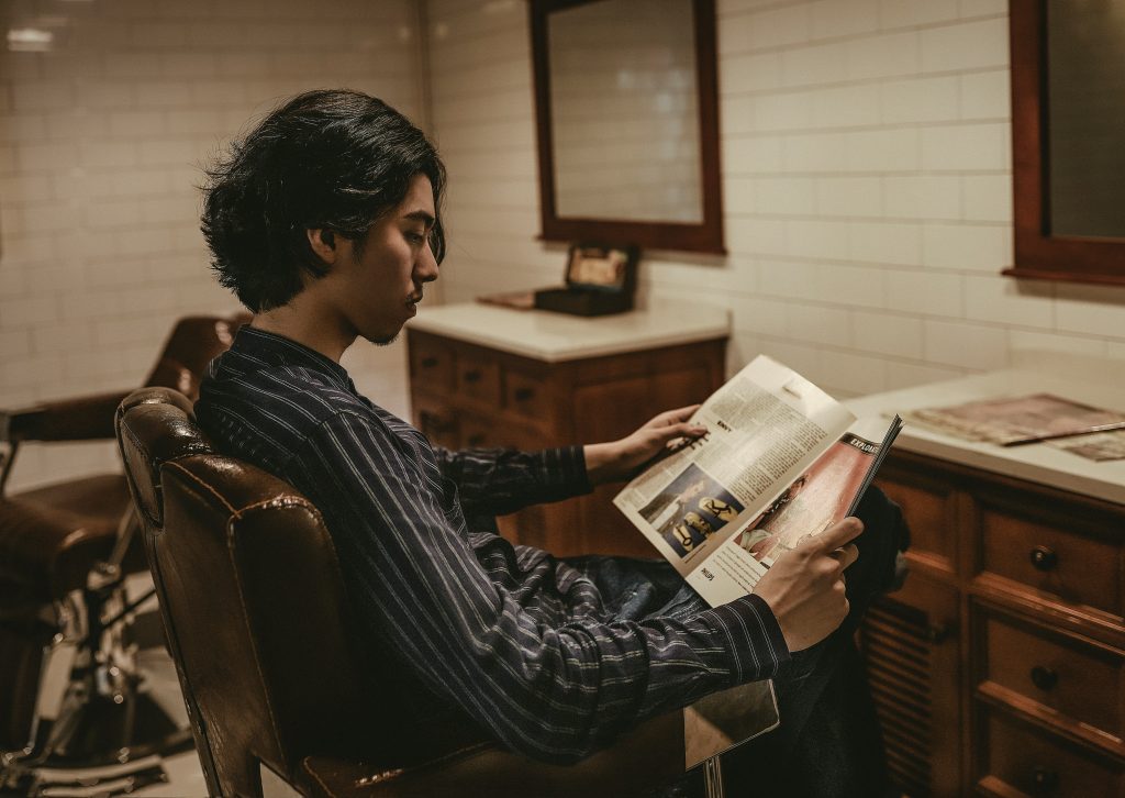 Man reading a book with phone turned off beside him.
