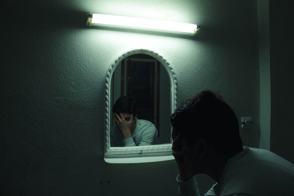 Man walking alone in a dim room symbolizing struggle and inner growth.