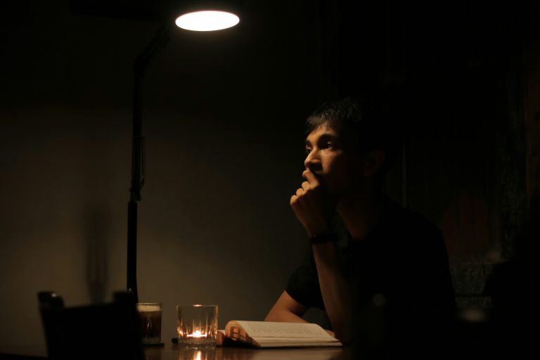 Man sitting calmly in a dark environment symbolizing how to build self control through mental discipline.