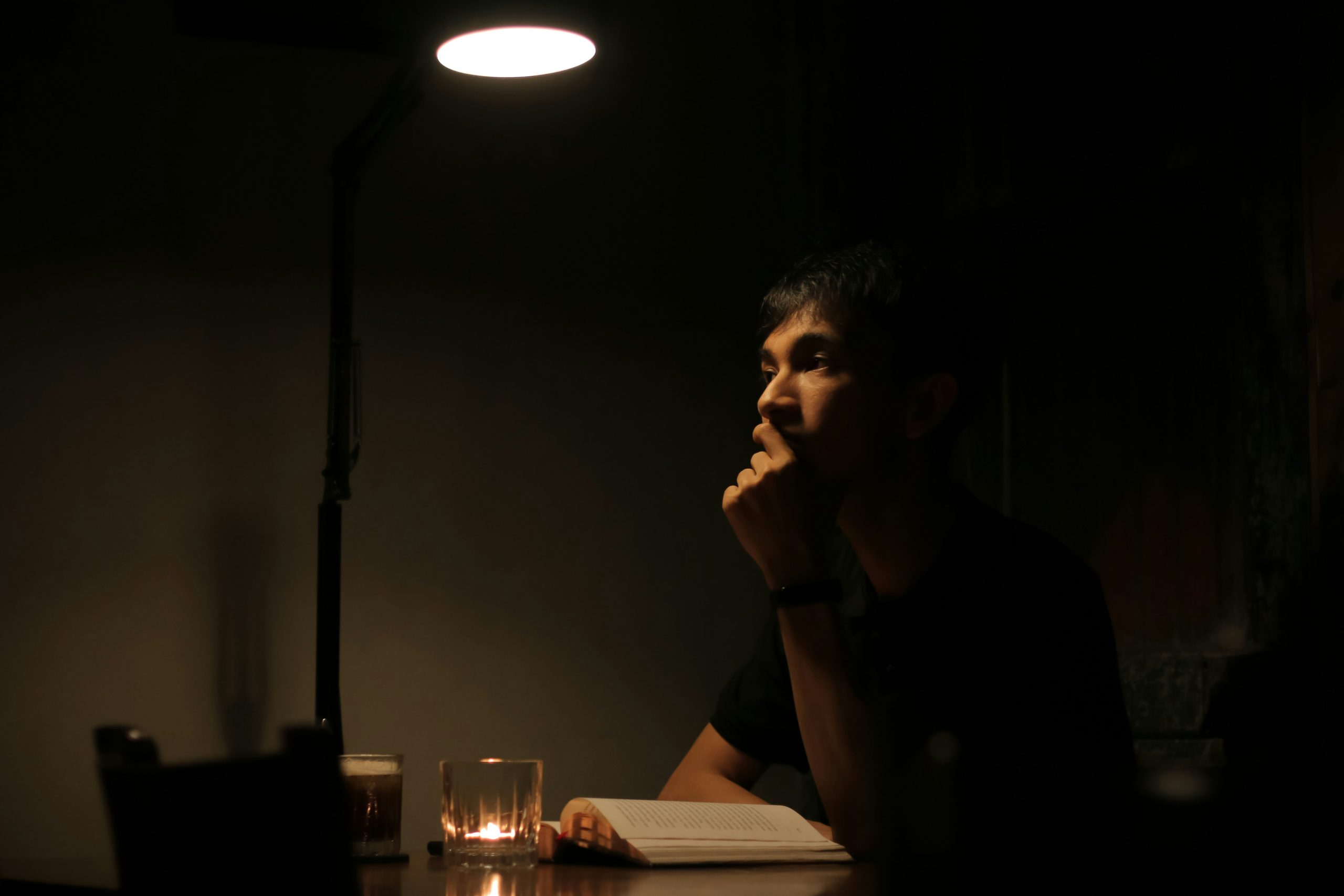 Man sitting calmly in a dark environment symbolizing how to build self control through mental discipline.
