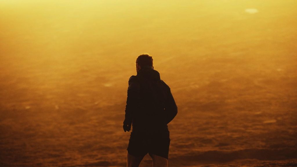 Silhouette of man walking alone toward sunrise, symbolizing daily discipline and direction.